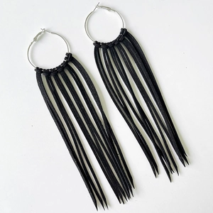 Detail of silver hoop earrings with thick black faux suede fringe tassels