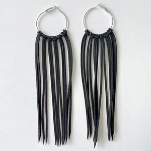 Macro detail of Bohemian oversized silver hoops with long black suede fringe tassels