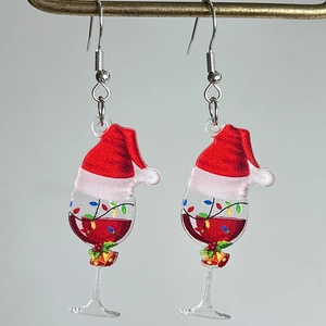 Detalle de pendientes navideños de acrílico con copa de vino, gorro de Papá Noel y cascabeles