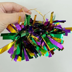 Macro shot of large festive hoop earrings with shiny green, purple, and gold metallic tassels