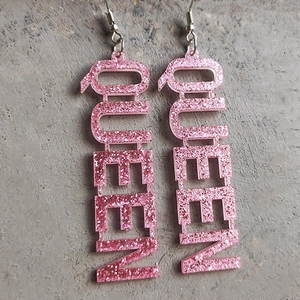 Détail de boucles d'oreilles Queen en acrylique à paillettes roses avec crochets métalliques