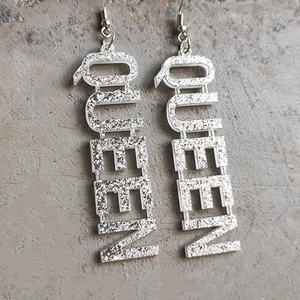 Détail macro des boucles d'oreilles pendantes QUEEN en acrylique pailleté argenté