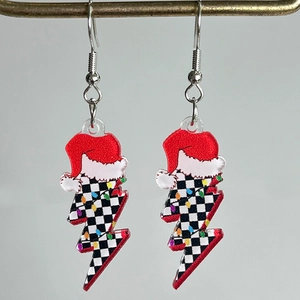 Detalle macro de pendientes de acrílico con forma de rayo, patrón de tablero y gorro de Navidad