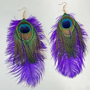 Dettaglio degli orecchini bohémien con piume viola e motivo a occhio di pavone