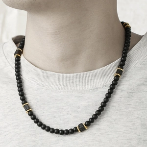 Men's matte black lava rock beaded necklace with gold metal accents on a male model