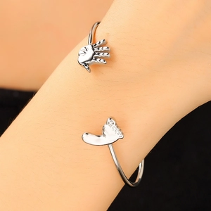Detail of silver baby foot and hand cuff bracelet with cubic zirconia on female wrist
