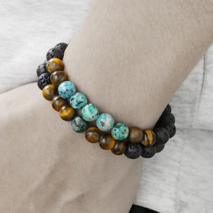 Tiger eye and volcanic stone beaded bracelets set for men worn on wrist over grey fabric