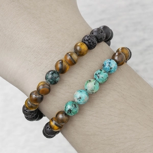 Detail of natural tiger eye and black lava stone beaded bracelets on male wrist