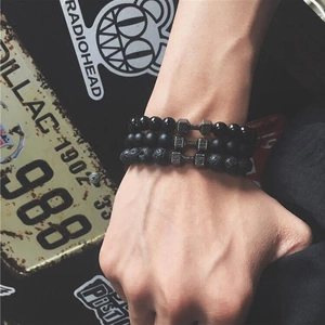 Détail de trois bracelets de fitness perlés en pierre de lave avec charmes haltères
