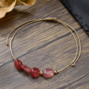 Dettaglio del bracciale intrecciato a mano con quattro pietre rosse e perline dorate