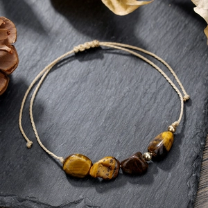 Dettaglio del bracciale intrecciato con pietre occhio di tigre e cordino regolabile su pietra