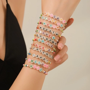 Detalle de pulseras bohemias de cuentas de colores con detalles dorados y letras de suerte