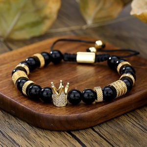 Dettaglio di bracciale in onice nero con corona dorata decorata con pietre di zircone