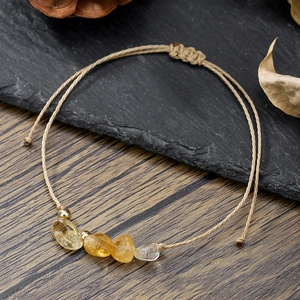 Dettaglio di pietre naturali e cordino marrone intrecciato su un bracciale regolabile