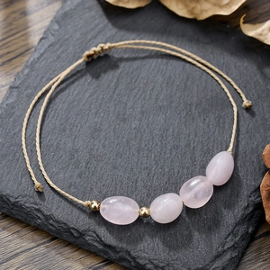 Dettaglio del braccialetto intrecciato a mano con pietre naturali rosa e nodo regolabile