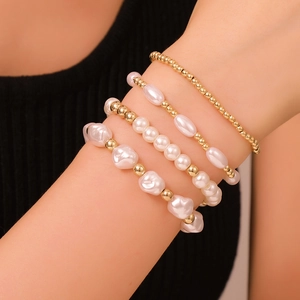 Set di bracciali a strati con perle dorate e perle d'acqua dolce sul polso di una modella
