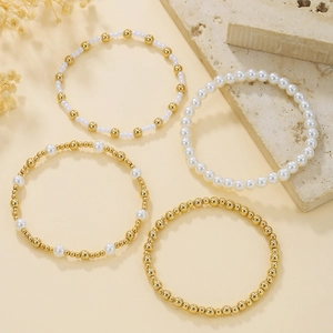 Dettaglio del set di quattro braccialetti con perle bianche e sfere dorate su base in pietra