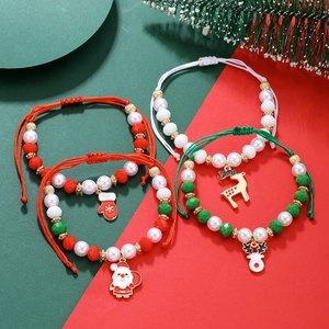 Detail of four Christmas charm bracelets with Santa and reindeer pendants on red-green background