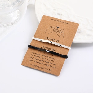 Detail of Morse code couples bracelets on card featuring engraved heart bar and woven cord