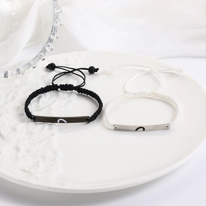 Macro shot of adjustable wax rope couple bracelets with engraved heart metal charms
