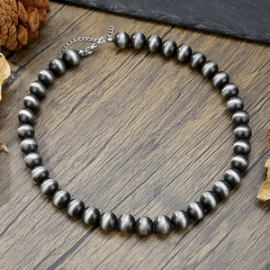 Gros plan du collier de perles Navajo avec perles gris brossé sur fond de bois naturel