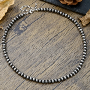 Gros plan de perles style Navajo en métal brossé sur un fond en bois rustique naturel