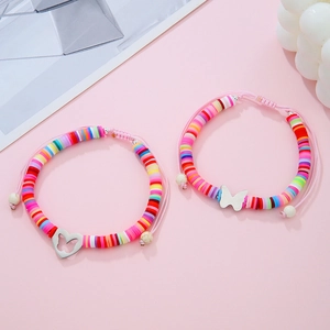 Dettaglio di due braccialetti Heishi arcobaleno fatti a mano con ciondoli a farfalla