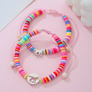 Dettaglio di braccialetti colorati in perline Heishi con ciondoli a cavallo e cordino