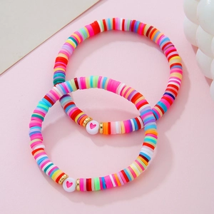 Dettaglio di braccialetti bohémien in perline heishi colorate con perline a cuore rosa