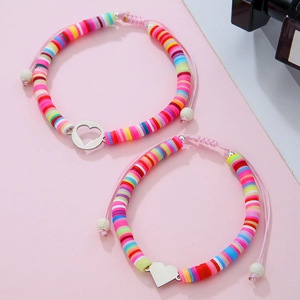 Dettaglio di braccialetti con perline rosa, ciondoli a cuore e cordini regolabili