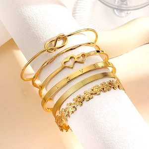 Detail van 6-delige gouden armbandenset met LOVE-gravure en infinity-knoop
