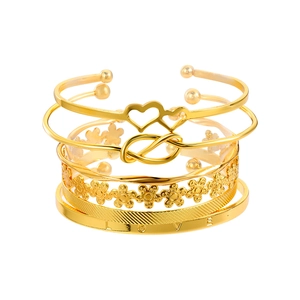 Detail van vergulde armbandset met hart, bloem, knoop en gegraveerde LOVE-tekst voor dames