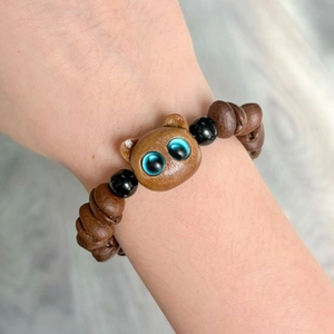 Handgemaakte geweven armband met houten kralen en kattenbedeltje om de pols