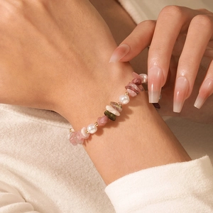 Detalle de pulsera de piedras naturales con perlas y cuentas doradas sobre un suéter