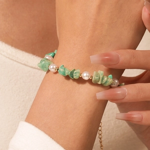 Detalle de una pulsera hecha a mano con perlas y piedras verdes en la muñeca