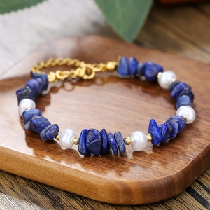 Pulsera de lapislázuli y perlas con cierre de acero inoxidable dorado sobre madera