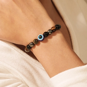 Detailansicht eines elastischen Perlenarmbands mit Evil Eye Anhänger und Lavastein