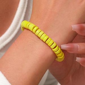 Detalle de una pulsera elástica amarilla vibrante con cuentas de madera planas