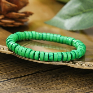 Foto macro de una pulsera elástica de cuentas de madera verde en mesa rústica