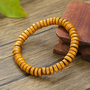 Primer plano de pulsera de cuentas de madera con veta natural en base rústica de madera
