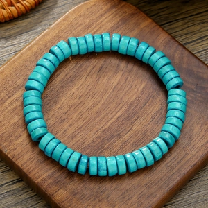 Detalle de cuentas cilíndricas turquesas en pulsera elástica sobre bloques de madera