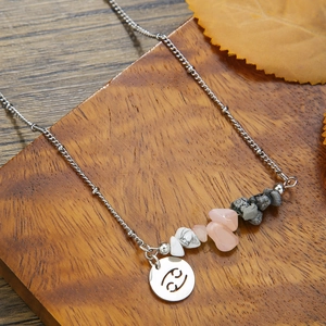 Detail of Cancer zodiac pendant with natural raw stones on a stainless steel chain