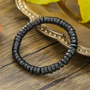 Detalle macro de una pulsera de cuentas de madera negra sobre superficie rústica
