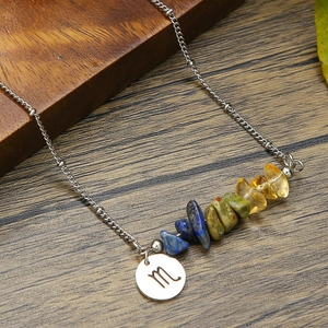 Macro view of Scorpio zodiac necklace with colorful natural stones on wooden background