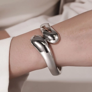 Close-up of a silver-toned irregular open cuff bracelet with polished teardrop ends