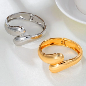 Polished double-headed snake spring bangle in gold and silver finish on white leather