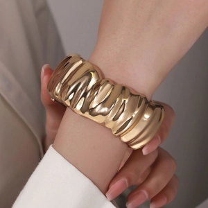 Macro detail of high-shine gold wavy cuff bracelet with modern mirror polish texture