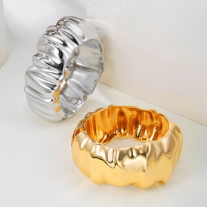 Detail of chunky textured cuff bracelet in gold and silver with elegant metal ripples