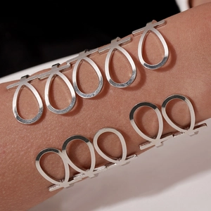 Detailed close-up of a silver stainless steel cuff bracelet with geometric teardrop cutouts