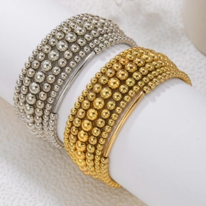 Pulseras de cuentas apilables en oro y plata con barras de metal pulido en soporte